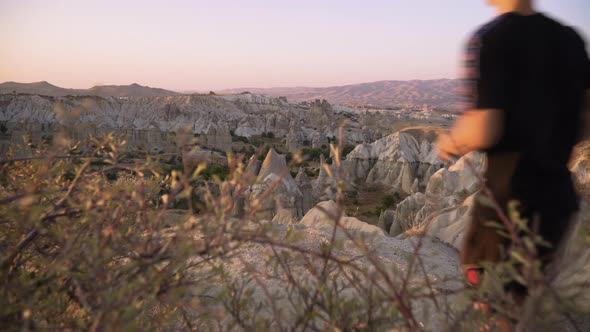 Young man runs towards a scenic viewpoint at sunset in Cappadocia