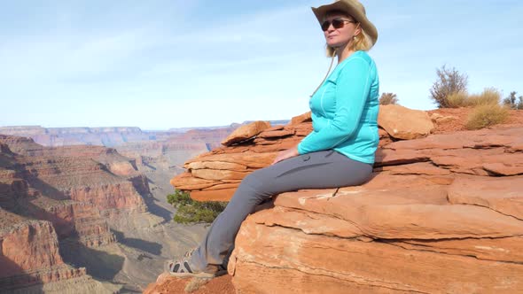 Woman Tourist Sitting On Rock Dangling Her Legs