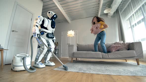 Girl Plays with a Droid While It Vacuum Cleans.