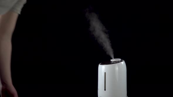 A Man Turned on an Ultrasonic Humidifier on an Isolated Black Background