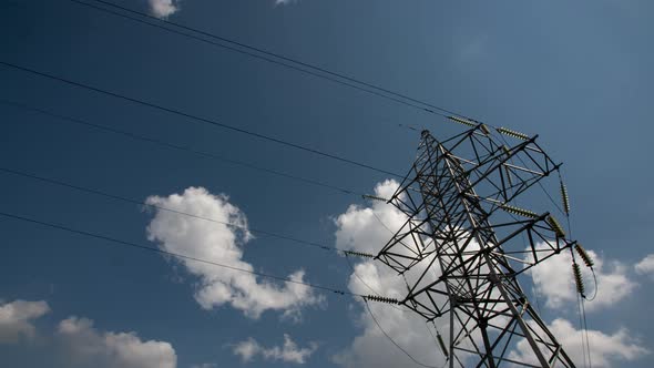 Power Transmission Lines High Voltage Electricity Grid with Cloudy Blue Sky on Background