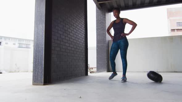 African american woman resting after exercising with medicine ball in an empty urban building