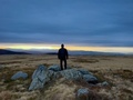 Rear view of man hiker standing on top of the cliffs admiring the sunset through the clouds - PhotoDune Item for Sale