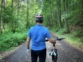 Rear view of man with helmet standing near his bicycle in the forest - PhotoDune Item for Sale