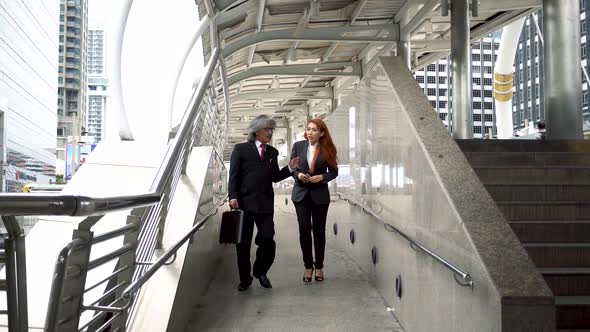 Senior Business Manager and Female Business Woman Walking in Hurry Over Urban City Background