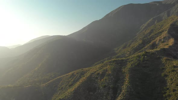 Aerial Pan and Tilt Down from a Verdant Mountain to a Winding Road