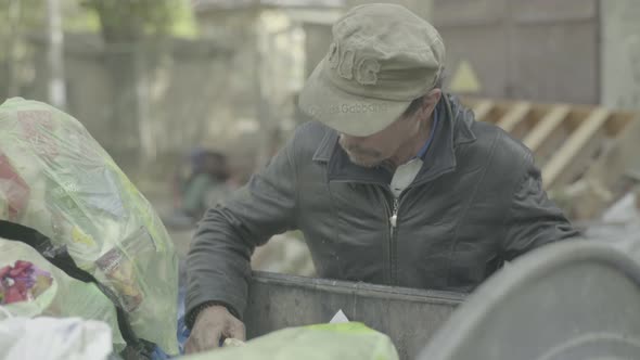 A Beggar Homeless Man Tramp Is Looking for Food in a Trash Can. Kyiv. Ukraine