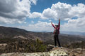 Man stands on top of a mountain with his arms raised in semi desert. - PhotoDune Item for Sale