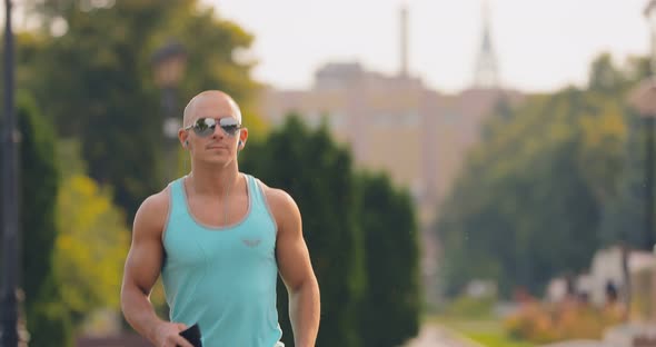 Man with Glasses and Headphones Runs Down the Street Summer Sunny Day