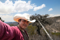 Man in a cowboy hat takes a selfie in front of a mountain. - PhotoDune Item for Sale
