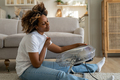 Happy young black woman sits in front of fan at home cooling down at home after being in heat - PhotoDune Item for Sale