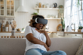 Shocked surprised young black woman sitting on sofa feeling scared in virtual reality - PhotoDune Item for Sale