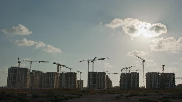 Timelapse of a large construction site with many cranes working over buildings