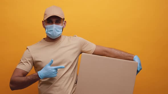 Courier with Face Mask Holding Backage and Pointing Finger Into It