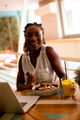 Young black woman having a healthy breakfast while working on laptop in the cafe - PhotoDune Item for Sale