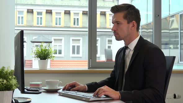 An office worker in a suit works serious on a computer