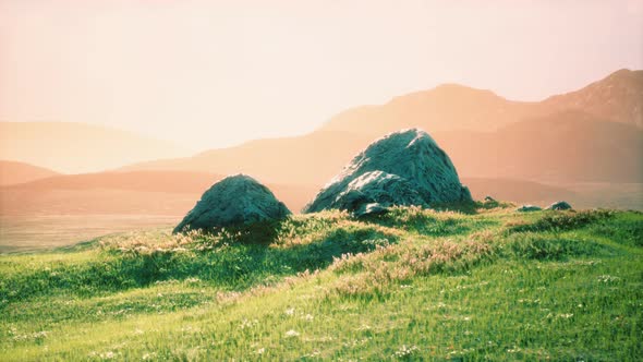 Meadow with Huge Stones Among the Grass on the Hillside at Sunset