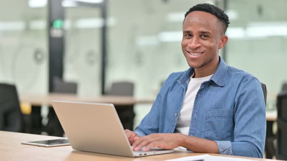Cheerful Casual African Man with Laptop Smiling at the Camera 