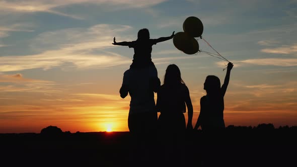 Family with Balloons at Sunset