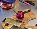Photo of a Large Red Onion sprouting at the top sitting on a wooden cutting board ready to be sliced - PhotoDune Item for Sale