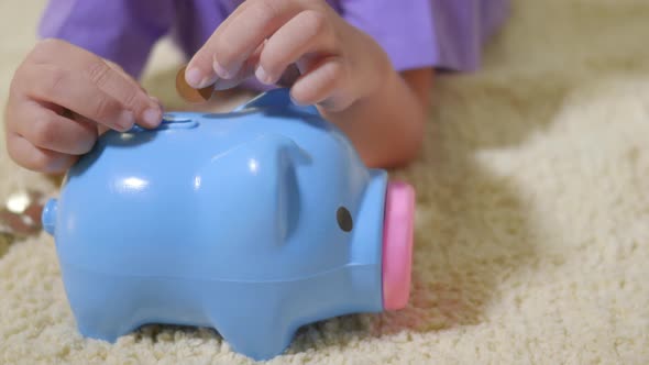 kid boy preschool putting pin money coins into blue faced piglet slot