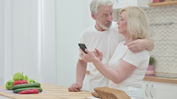 Old Couple Working on Laptop &amp; Smartphone in Kitchen