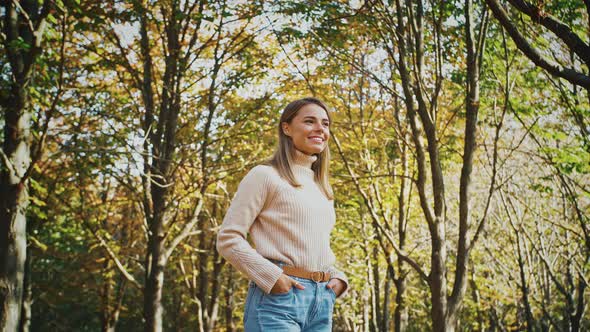 Young Attractive Lady Smiling and Looking at you While Posing with Her Hands in Pockets Standing at