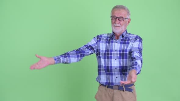 Happy Senior Bearded Hipster Man Showing Something and Giving Thumbs Up