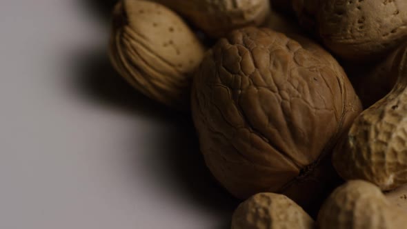 Cinematic, rotating shot of a variety of nuts on a white surface 