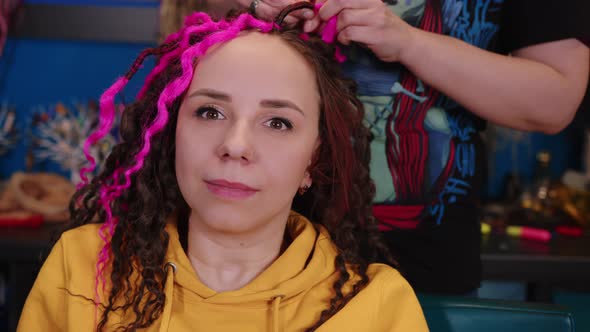 Unrecognizable Person Makes Curly Hairstyle for Young Woman in Salon