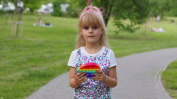 Child Girl Kid Playing Push Pop It Bubble Fidget Toy in Park Stress Anxiety Relief Squeeze Sensory