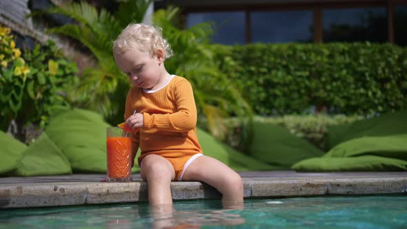 A Cute Child is Sitting By the Pool Drinking a Healthy Tropical Fruit Smoothie