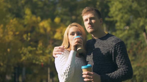 Couple Tasting Hot Drinks in Park and Hugging, Romantic Date, Coffee-To-Go