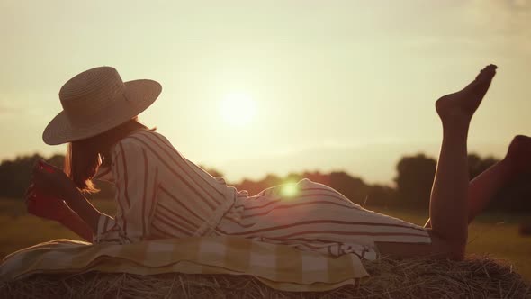 Beautiful girl in a hat lies on a haystack