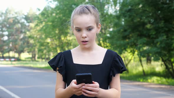 Teenage Girl in Black Dress Enjoys Happy News Closeup