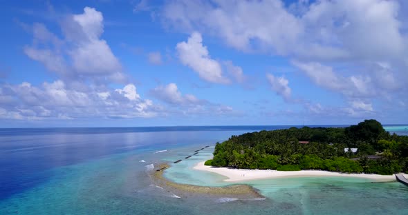 Daytime aerial island view of a sandy white paradise beach and aqua blue water background in vibrant