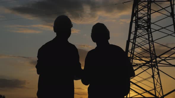 Silhouette of Engineers Looks at the Construction of High-voltage Power. Teams Engineer Looking