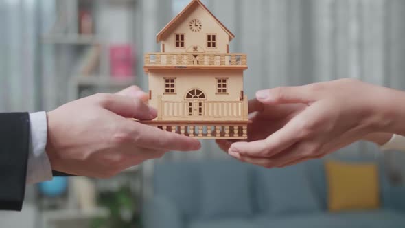 Close Up Of Real Estate Agent's Hand Giving The House Model To A Woman In The House For Sale