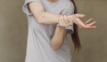 Young woman with hand convulsions pain ache against brown background. - PhotoDune Item for Sale