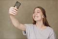 Young woman making selfie mobile phone at brown background. - PhotoDune Item for Sale