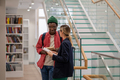 Smiling african american guy student communication with european girlfriend in university library - PhotoDune Item for Sale
