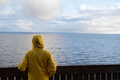 Man tourist in yellow raincoat watching sea on cold cloudy day looking at water, listening waves - PhotoDune Item for Sale