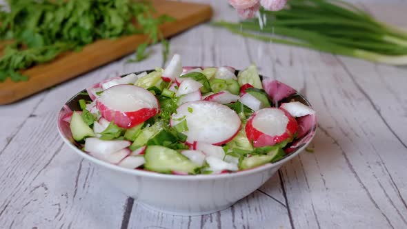 Hands Chef Sprinkles Salt on a Vegetable Salad with Radish Cucumber Greens