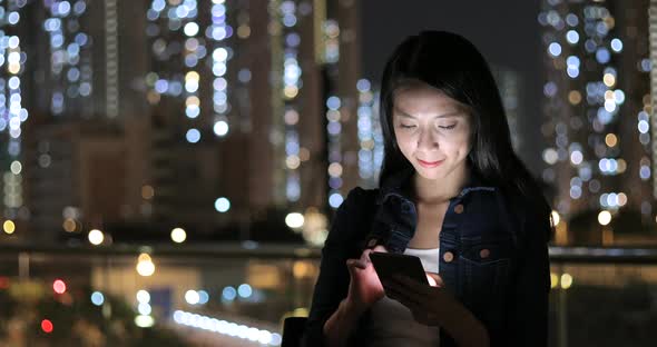 Woman using mobile phone in city at night 