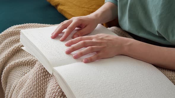 Blind Woman Reading Braille Book Sitting on Sofa Touching Letters on Sheet of Paper Using His