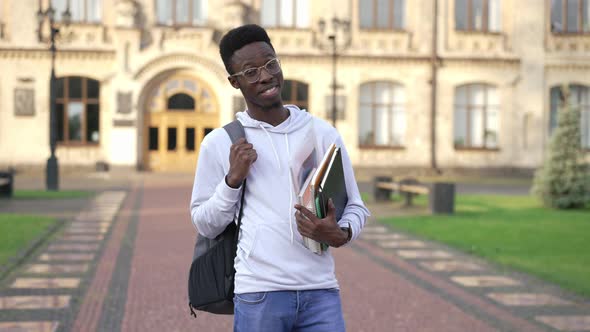 Portrait of Satisfied African American Young Male Student Posing Outdoors at University Campus in