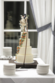 Four tiered ivory colored wedding cake on table at wedding reception. - PhotoDune Item for Sale