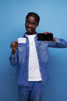 stylish american man with black dreadlocks holding money card mockup and smartphone