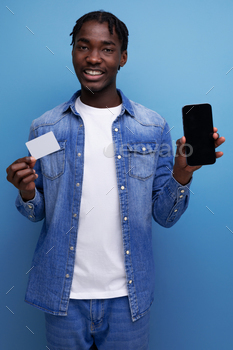 charismatic american man with black dreadlocks making payment with money card and smartphone