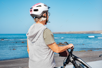 eascape enjoying a sunny day at the beach riding electric bicycle. Authentic retirement living and healthy lifestyle concept.